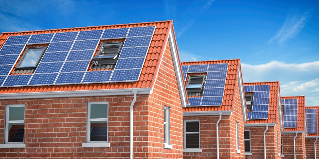 Row of Brick Houses with solar panels on roof on blue sky background.