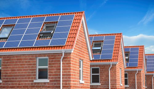 Row of Brick Houses with solar panels on roof on blue sky background.